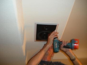 Using a cordless drill to screw in the speakers using caution not to over tighten	