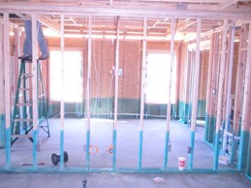 The unfinished wall where the HDTV, speakers, and home theater components will go when finished with a look at the bedroom seen through the unfinished 2x4s